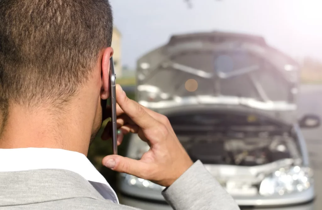 man standing by the broken vehicle calling tow service